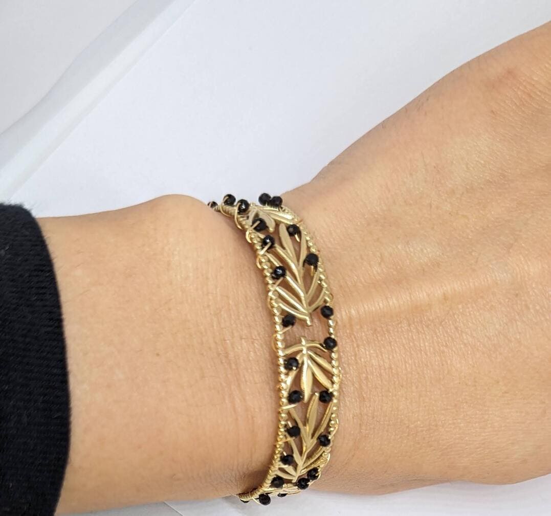 Bracelet femme en acier inoxydable doré orné de pierres naturelles noires.