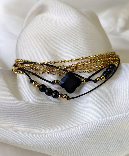 Gourmette en chaîne maille boulle doré et fil noir orné de trèfle et pierres noires.