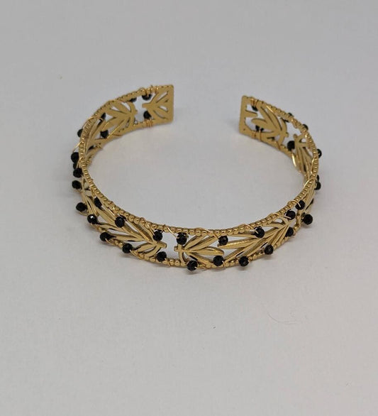 Bracelet femme en acier inoxydable doré orné de pierres naturelles noires.